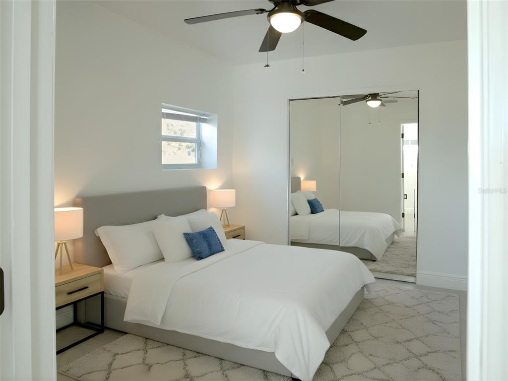 A bedroom features a bed with white bedding, a mirrored closet, and a ceiling fan — 15201 BAILEY HILL ROAD, BROOKSVILLE, FL