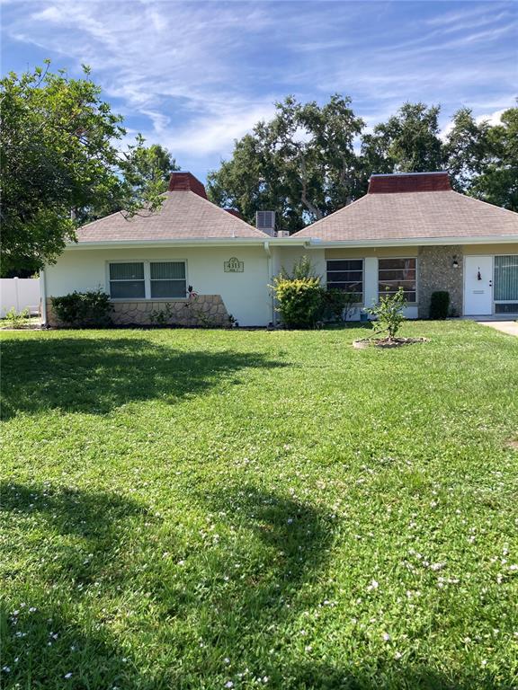 A single-story duplex with a light-colored exterior, stone accents, and two matching pyramid-style roofs — 4313 TAHITIAN GARDENS CIRCLE CIRCLE UNIT B, HOLIDAY, FL