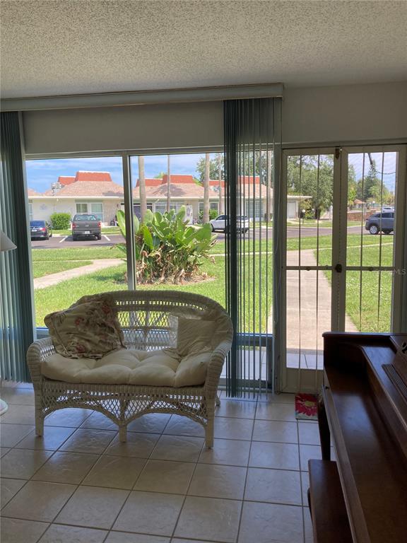 A sunroom with tile flooring, a wicker loveseat, and a view of a residential parking area — 4313 TAHITIAN GARDENS CIRCLE CIRCLE UNIT B, HOLIDAY, FL