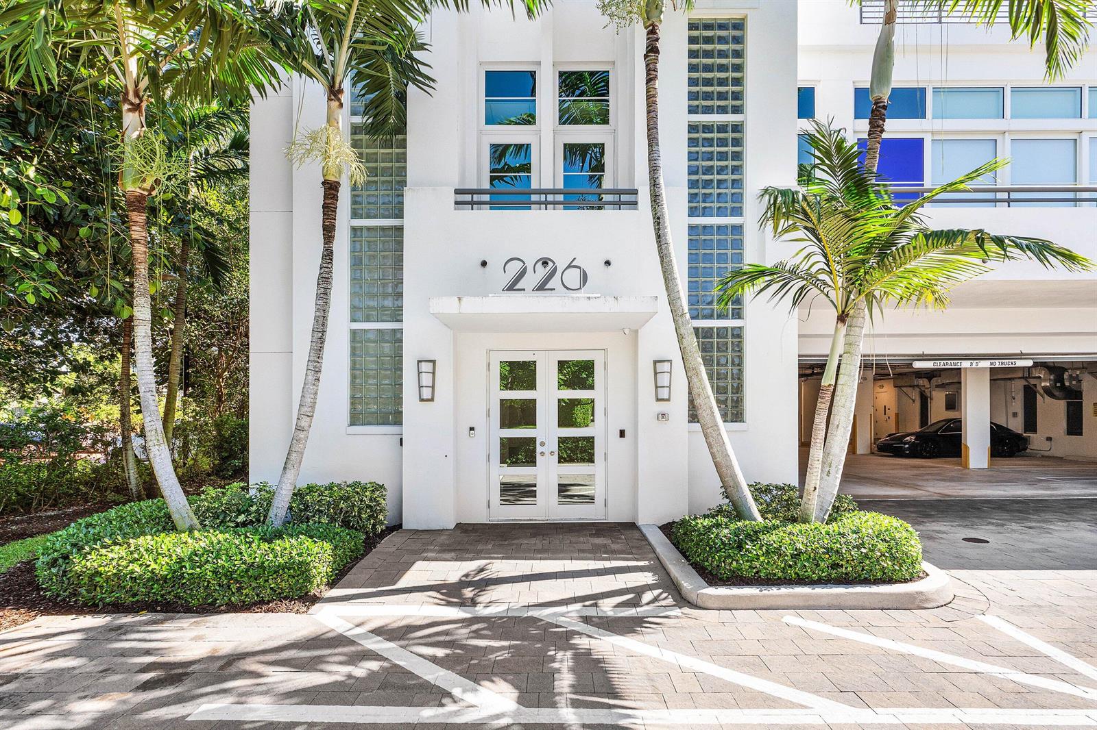 The exterior of a white building with glass block windows, palm trees, and a parking garage — 226 Palm Court, Delray Beach FL 33444, DELRAY BEACH, FL