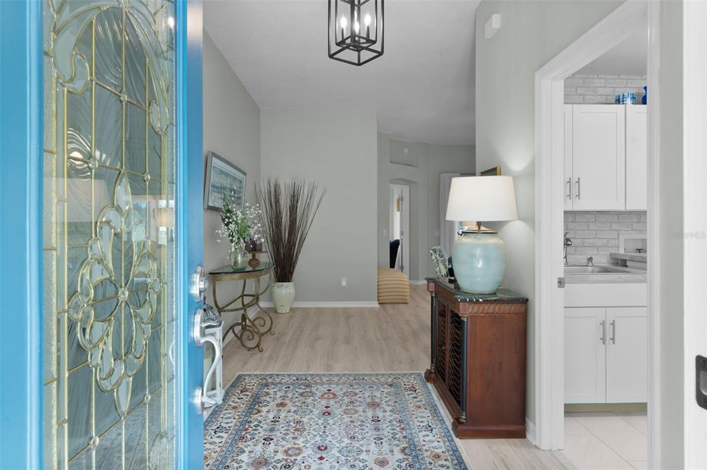 An entryway with a blue door, patterned rug, and a view into a kitchen area — 2132 SANSORES STREET, THE VILLAGES, FL