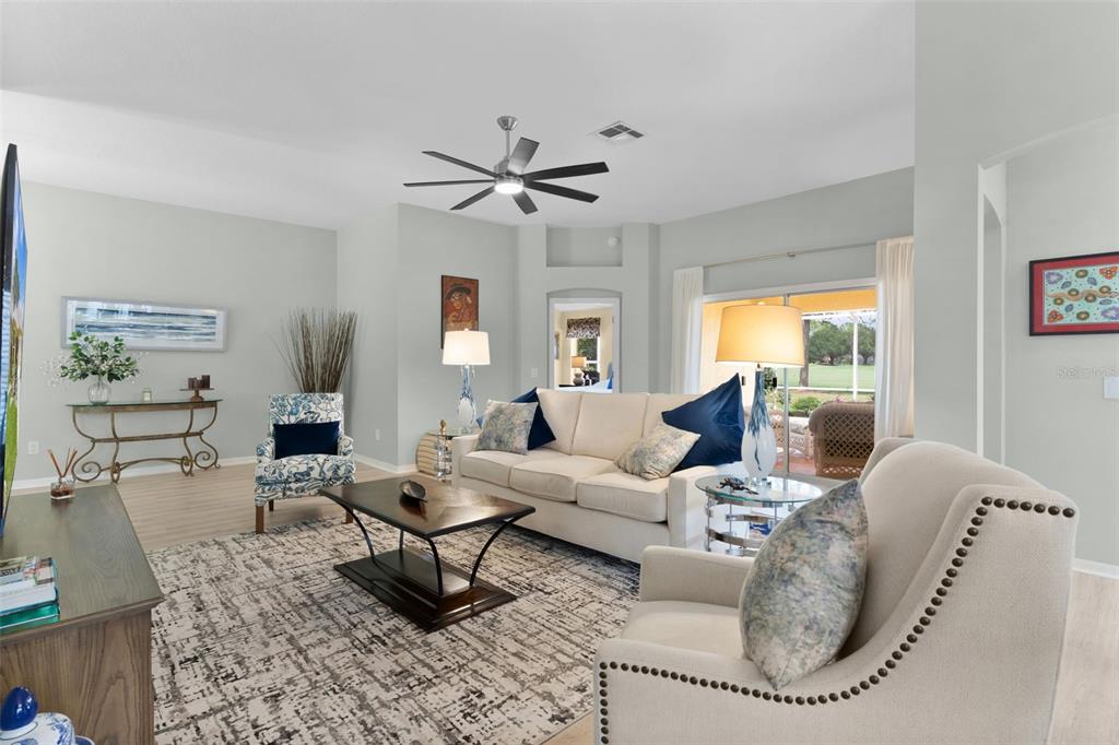 A living room features a beige sofa, patterned armchair, area rug, and sliding glass doors — 2132 SANSORES STREET, THE VILLAGES, FL