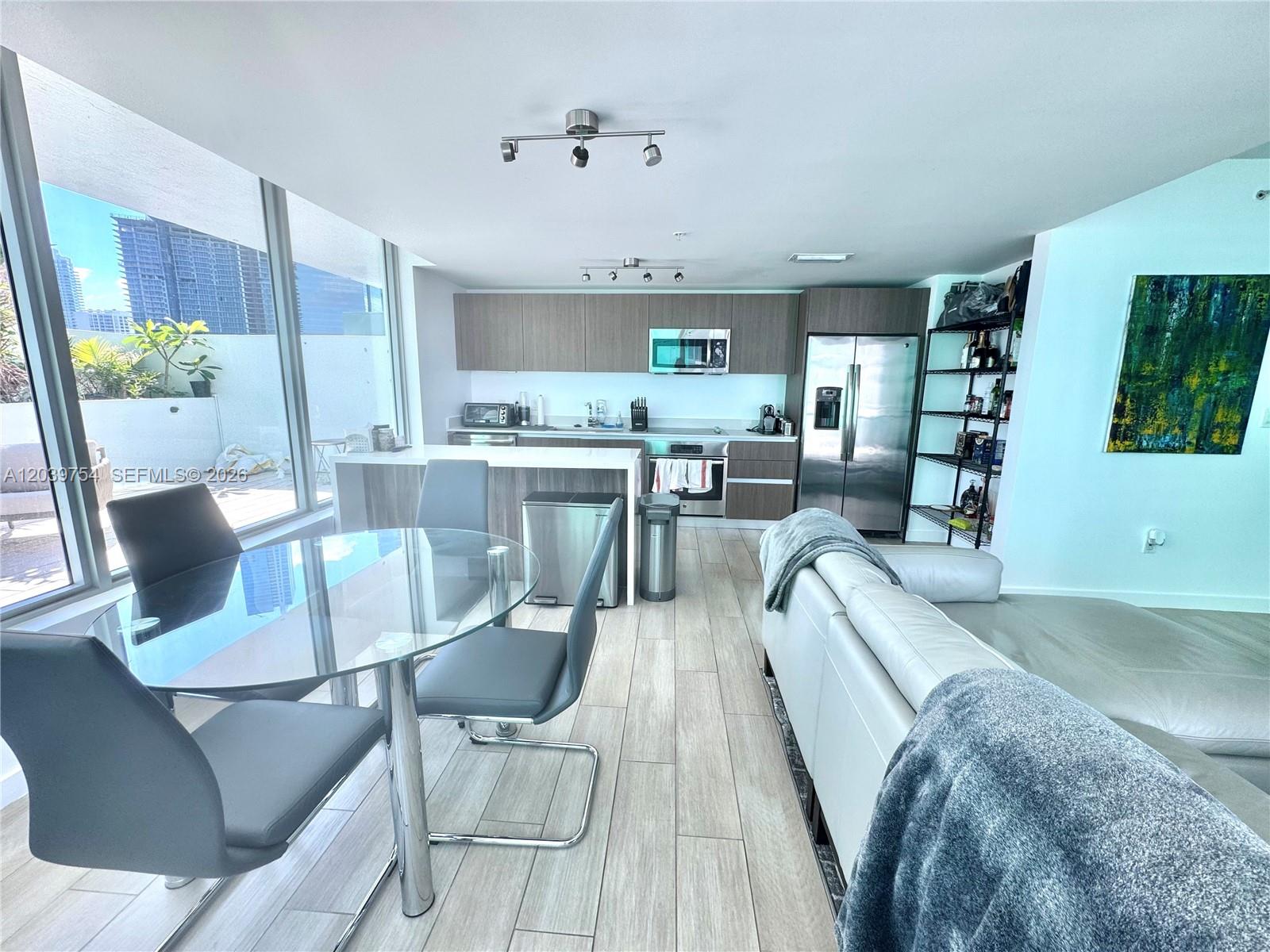 An open-concept kitchen and dining area features a glass table, modern cabinetry, and floor-to-ceiling windows — 1600 SW 1st Ave # 910, Miami FL 33129, MIAMI, FL