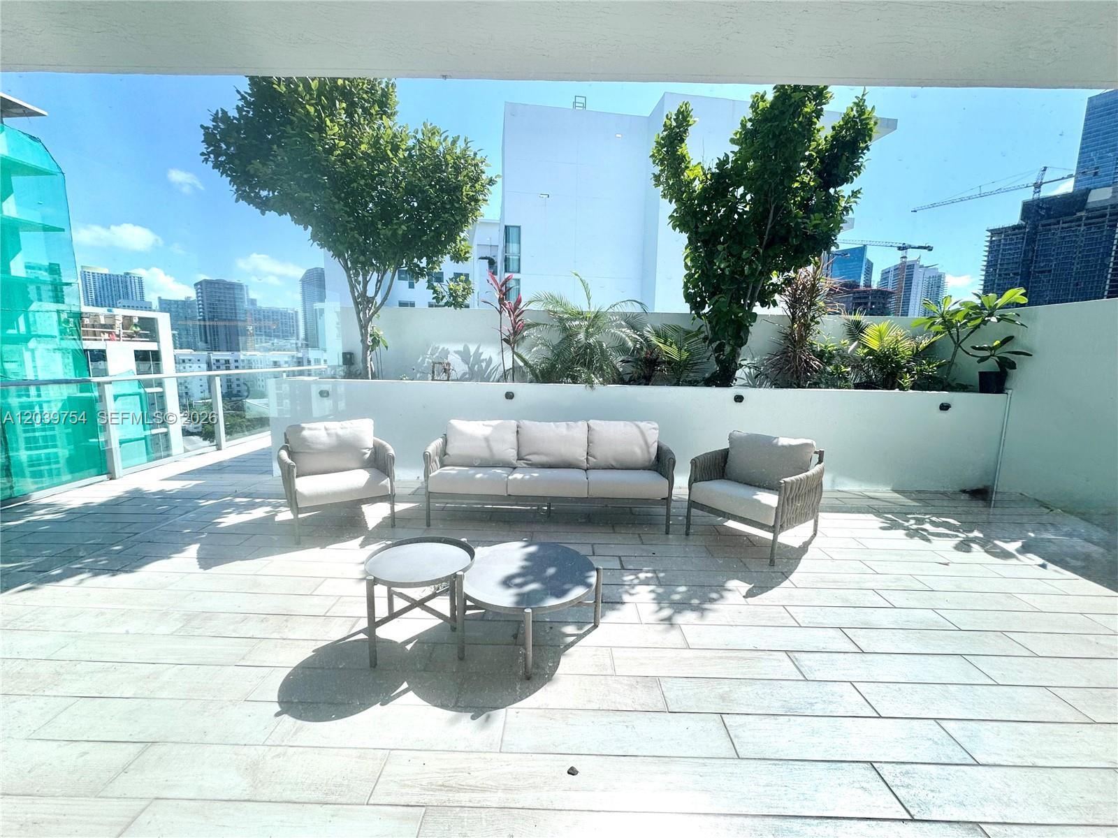 A furnished outdoor terrace features a sofa, two armchairs, and two round coffee tables — 1600 SW 1st Ave # 910, Miami FL 33129, MIAMI, FL