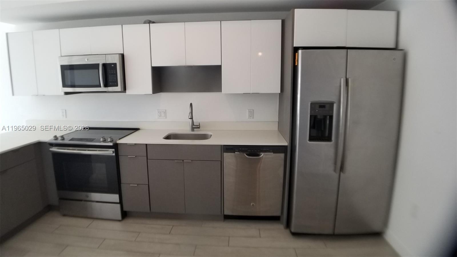 A kitchen features stainless steel appliances, white upper cabinets, and grey lower cabinets — 321 NE 26th St # 511, Miami FL 33137, MIAMI, FL