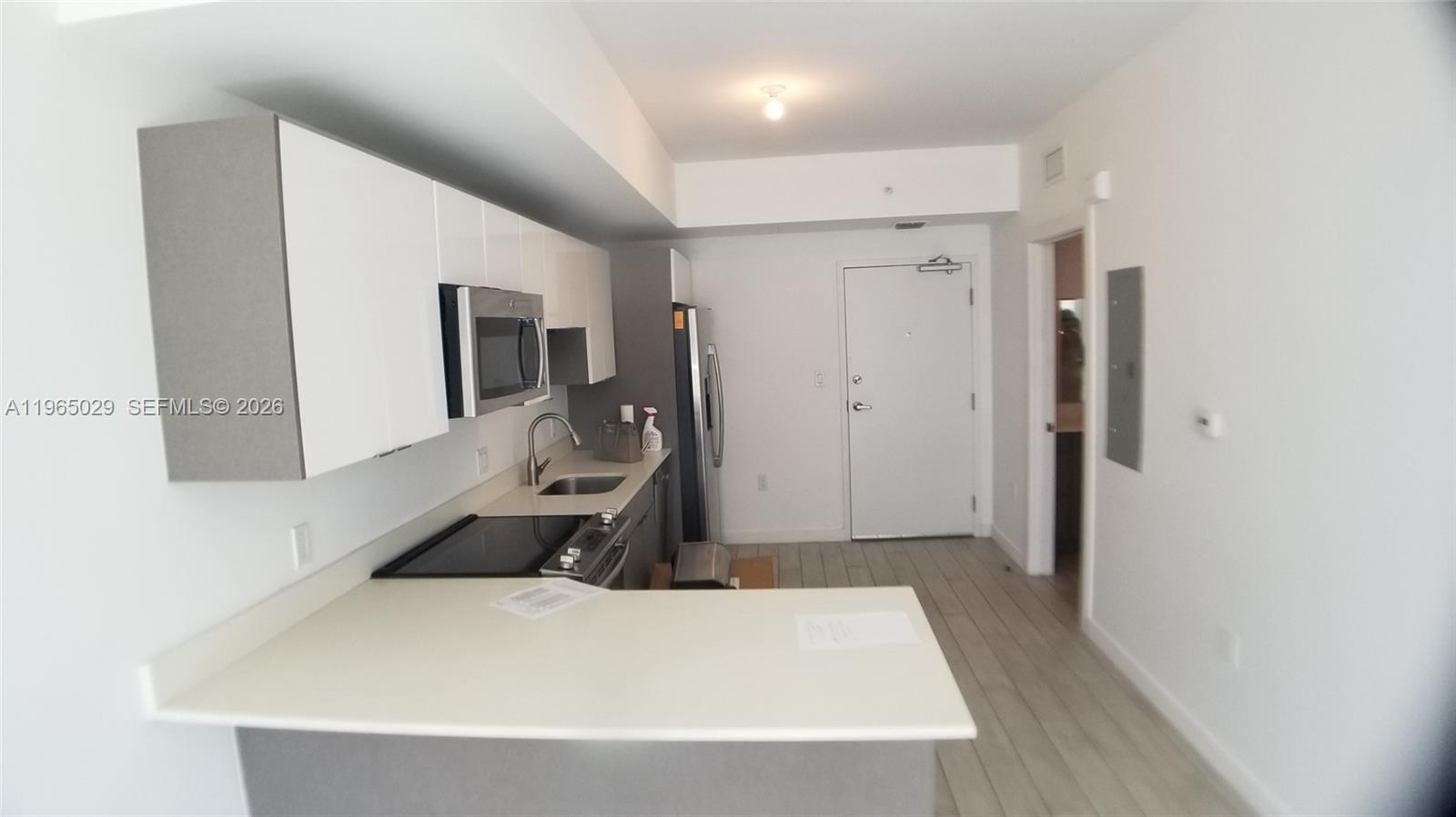 A modern kitchen features white cabinets, stainless steel appliances, and a peninsula countertop — 321 NE 26th St # 511, Miami FL 33137, MIAMI, FL