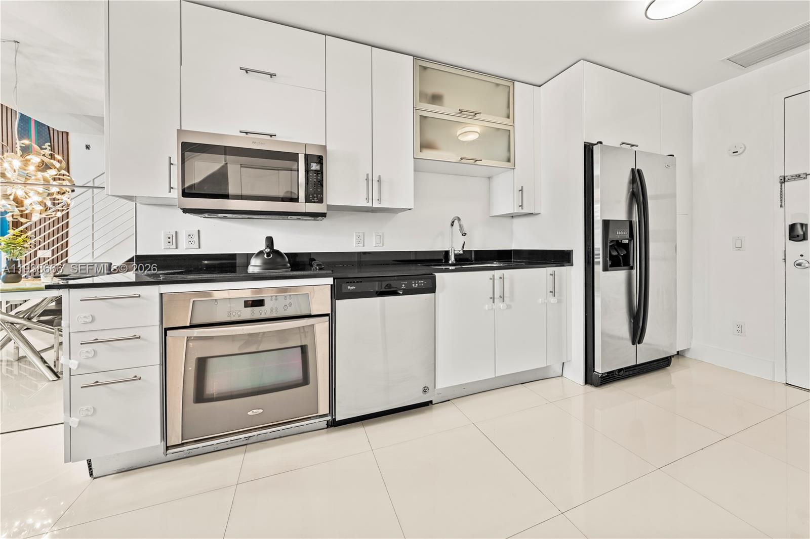 A modern kitchen features white cabinets, stainless steel appliances, and black countertops — 60 SW 13th St # 2422, Miami FL 33130, MIAMI, FL