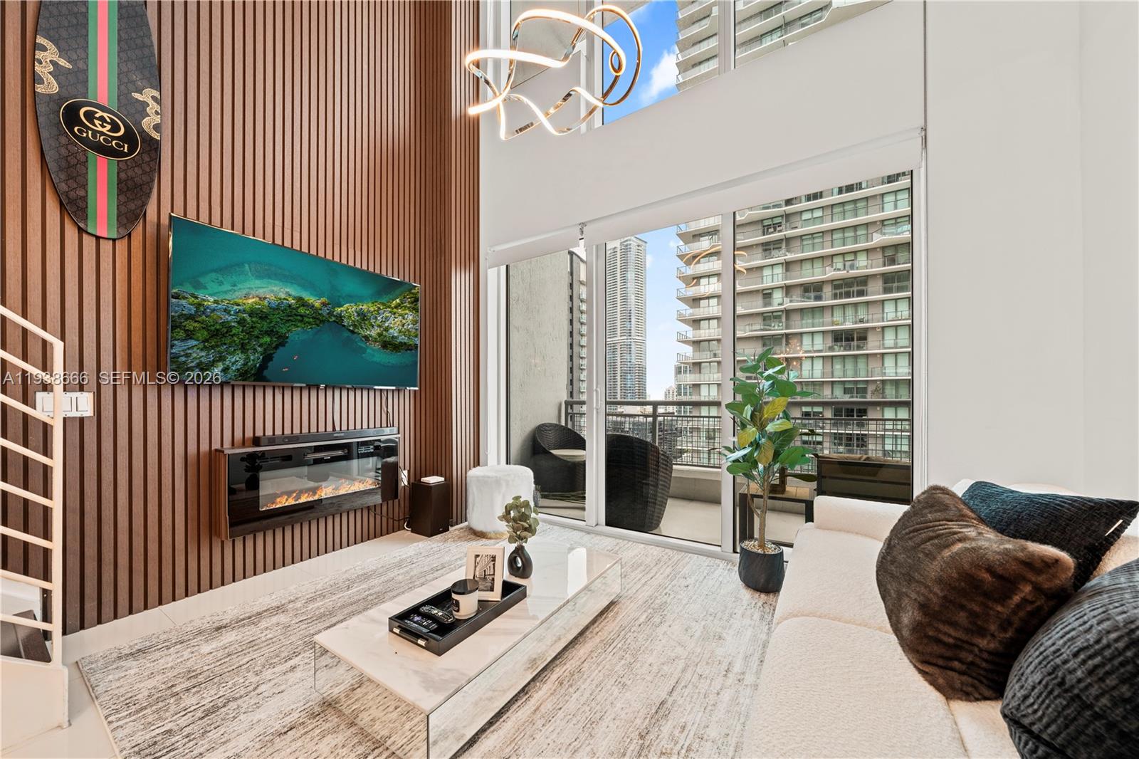A modern living room features wood-slat walls, a fireplace, a large television, and floor-to-ceiling windows — 60 SW 13th St # 2422, Miami FL 33130, MIAMI, FL