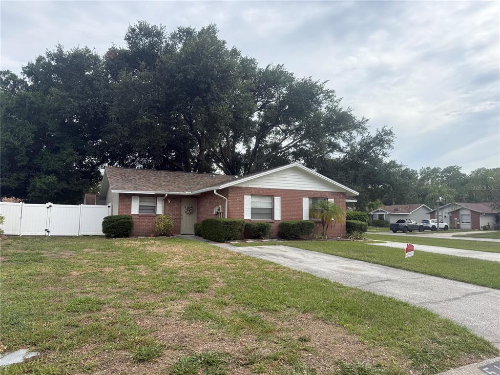 A single-story brick house with a white fence and a large tree in the yard — 5118 LETITIA COURT, TAMPA, FL