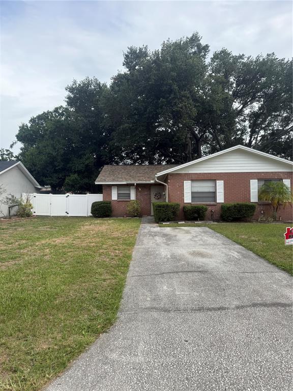 A single-story brick house features a concrete driveway, white fence, and large trees — 5118 LETITIA COURT, TAMPA, FL