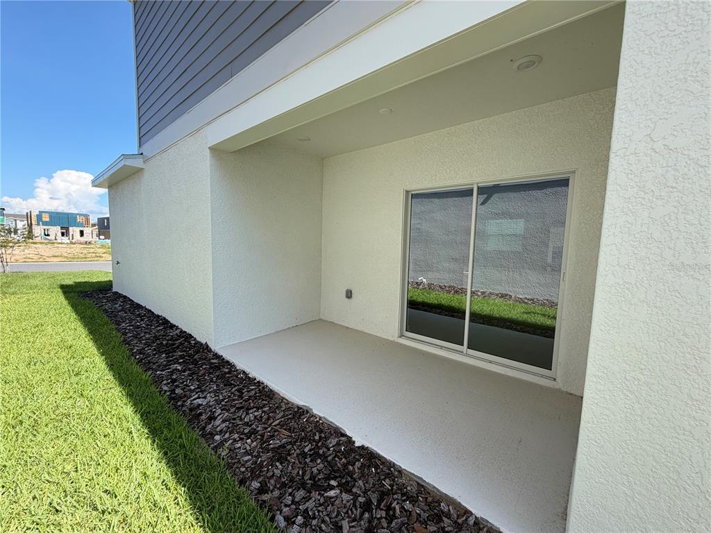 A covered concrete patio features a sliding glass door and recessed lighting — 6017 WELLBEING WAY, CLERMONT, FL