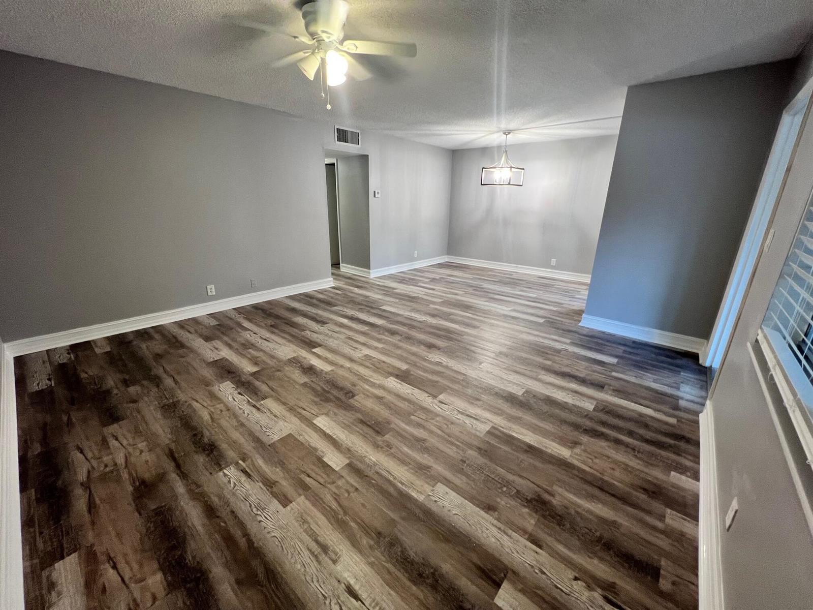 An empty room with gray walls, wood-look flooring, a ceiling fan, and a light fixture — 1340 NE 28th Avenue # 243, Pompano Beach FL 33062, POMPANO BEACH, FL