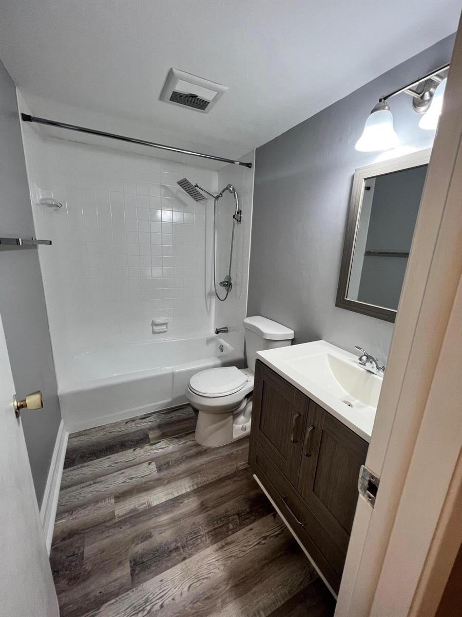 A bathroom features a white tub-shower combo, a dark wood vanity, and gray flooring — 1340 NE 28th Avenue # 243, Pompano Beach FL 33062, POMPANO BEACH, FL