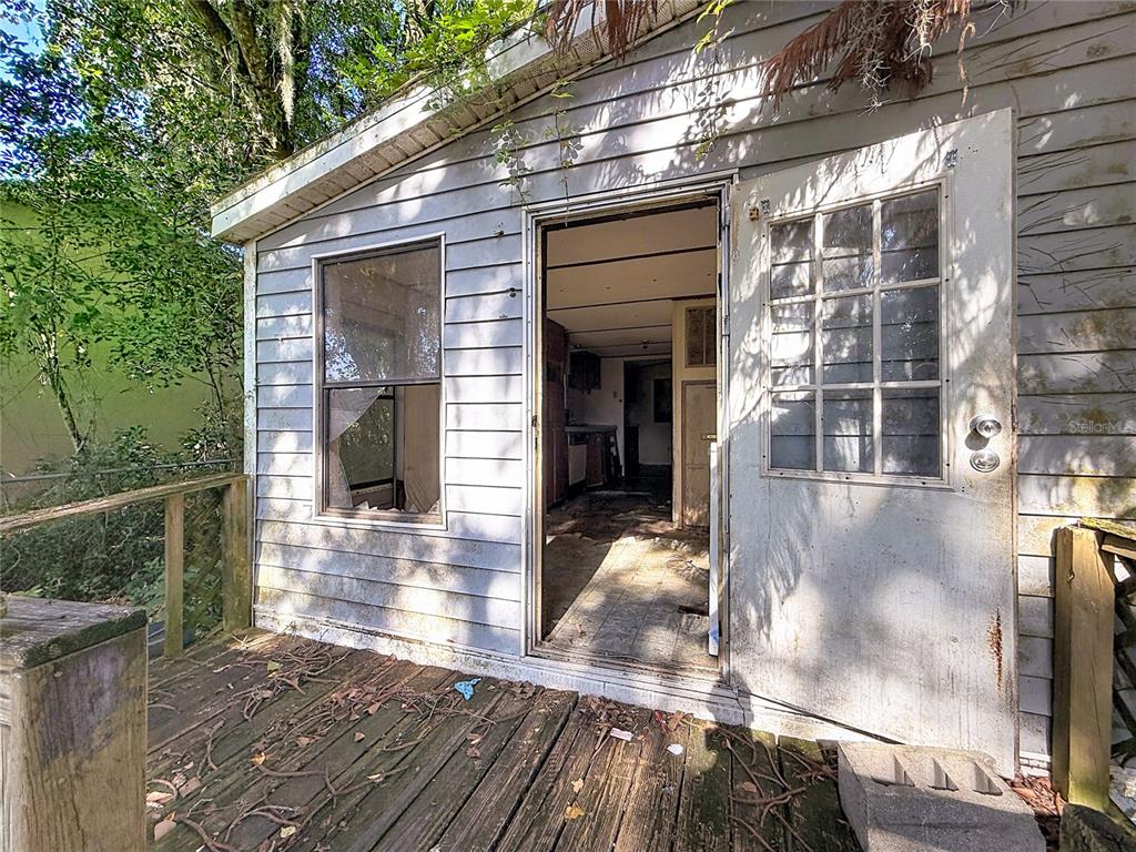 An exterior view of a weathered shed with a wooden deck and an open doorway — 8216 SIMPSON LANE, LAKELAND, FL