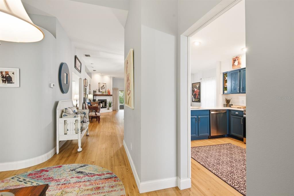 A hallway leads to a living area with a fireplace, adjacent to a blue-cabinet kitchen — 11328 HOLLANDER AVENUE, HUDSON, FL