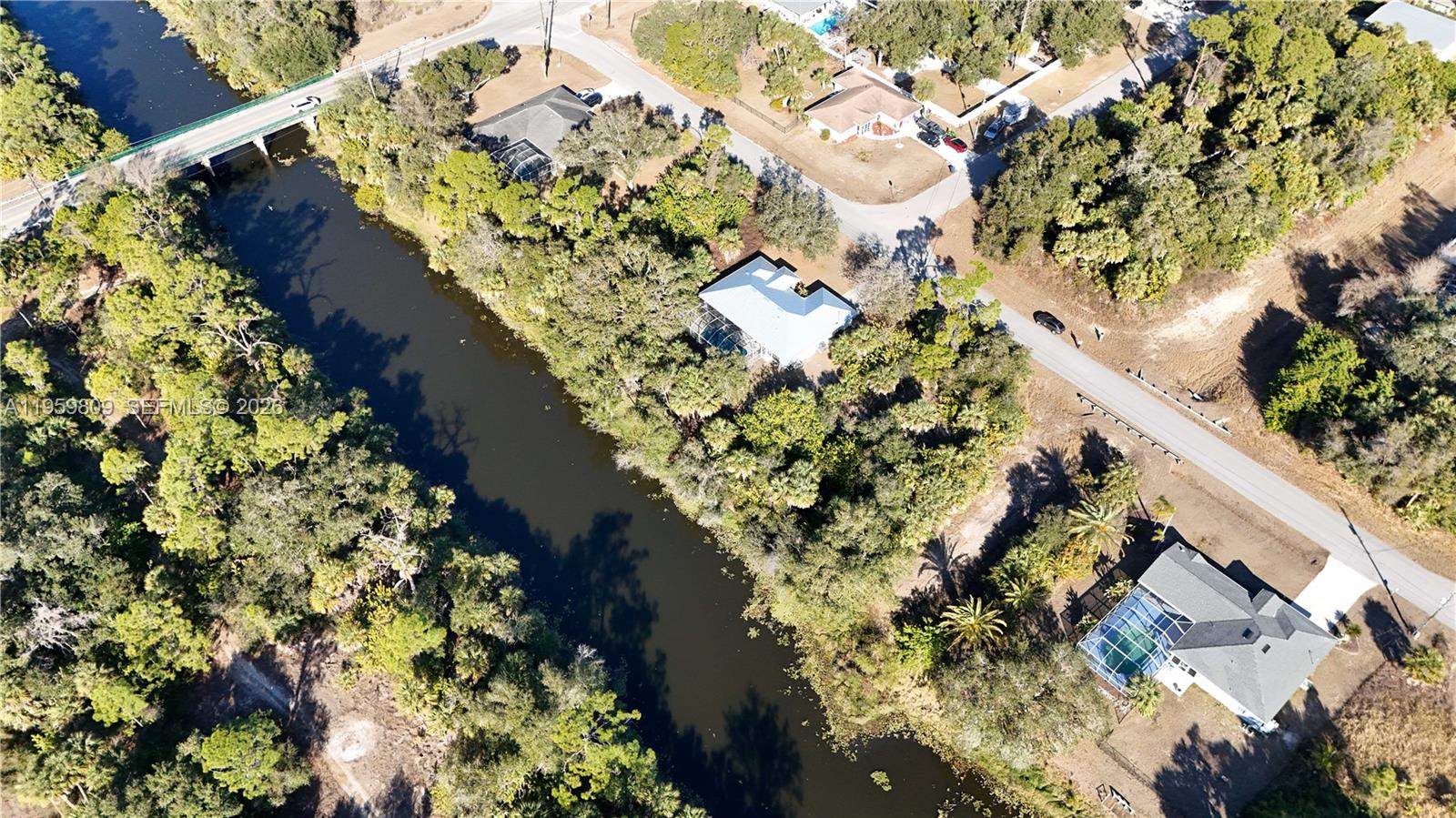 An aerial view shows a canal flowing past several houses surrounded by dense trees — 0 Adelaide Ave, North Port FL 34288, NORTH PORT, FL