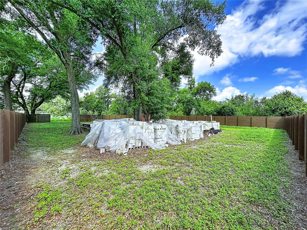 A backyard features a large pile of concrete blocks covered by a plastic tarp — 1029 ROBSON AVENUE, SEFFNER, FL