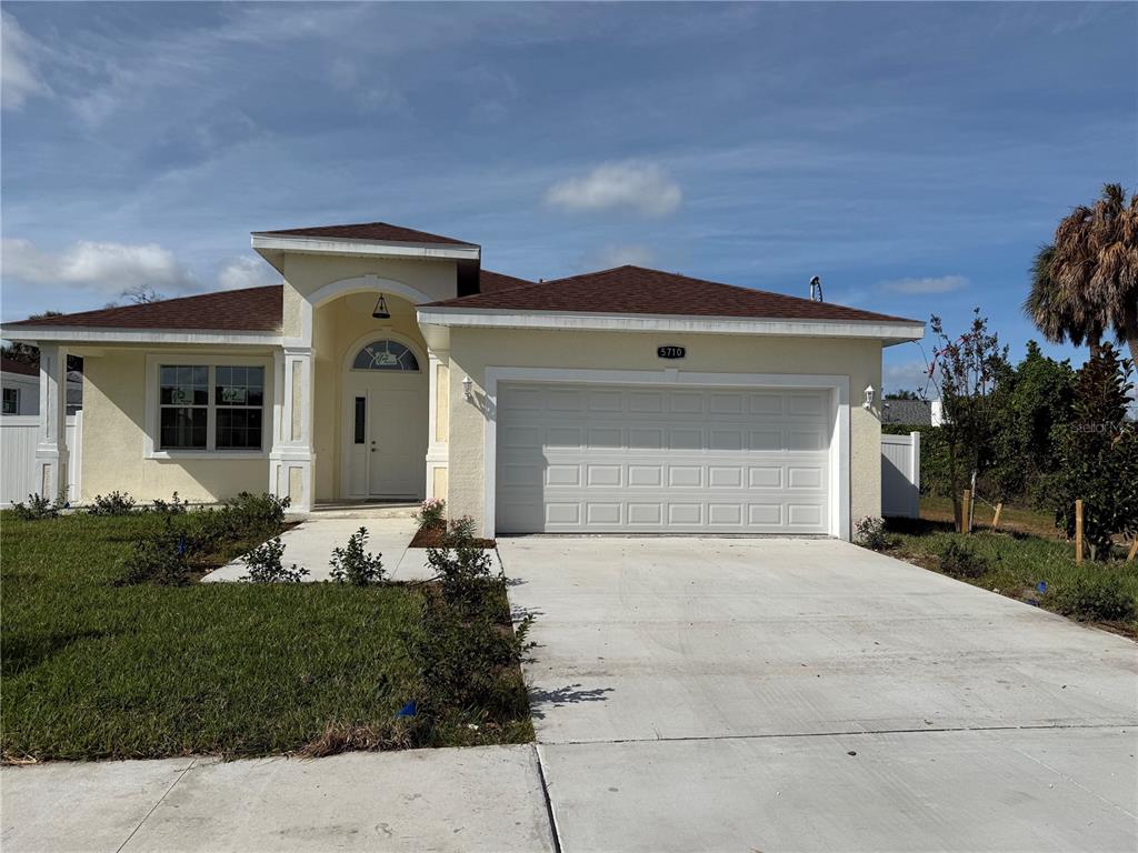 A single-story house with a light yellow exterior, a two-car garage, and a brown roof — 5710 42ND STREET N, ST PETERSBURG, FL