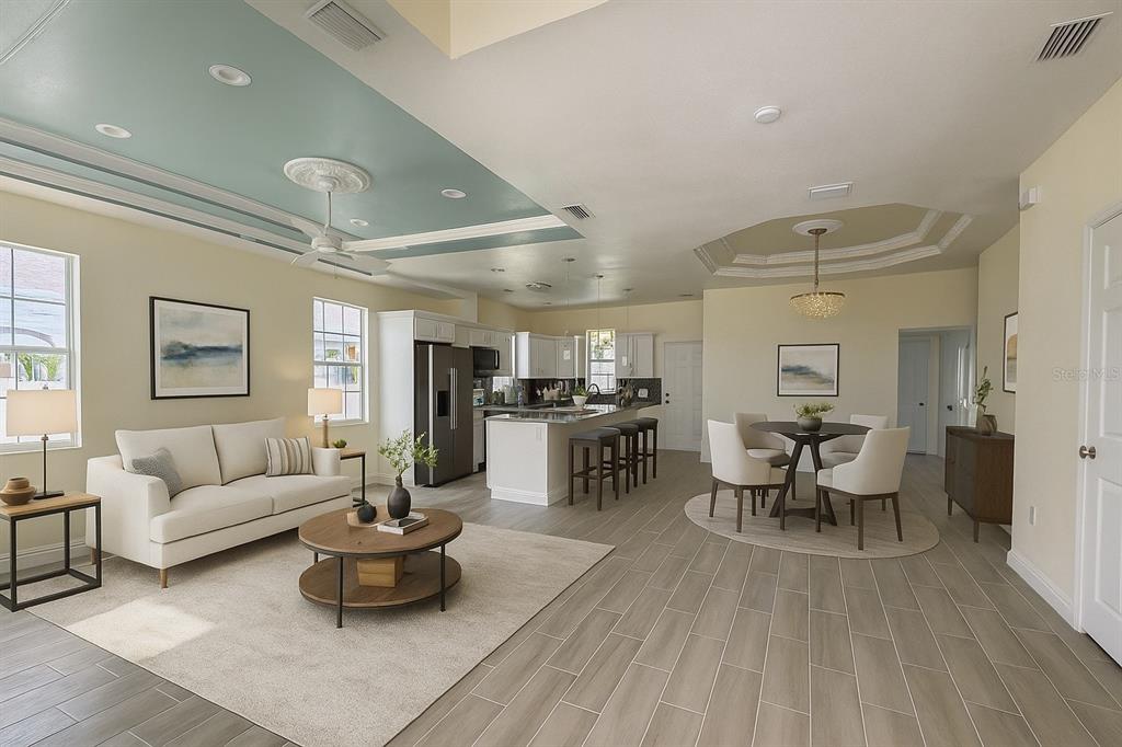 An open-concept living and dining area features a blue tray ceiling and tile flooring — 5710 42ND STREET N, ST PETERSBURG, FL