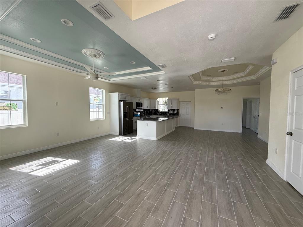 An open-concept kitchen and living area features wood-look tile flooring and a blue tray ceiling — 5710 42ND STREET N, ST PETERSBURG, FL