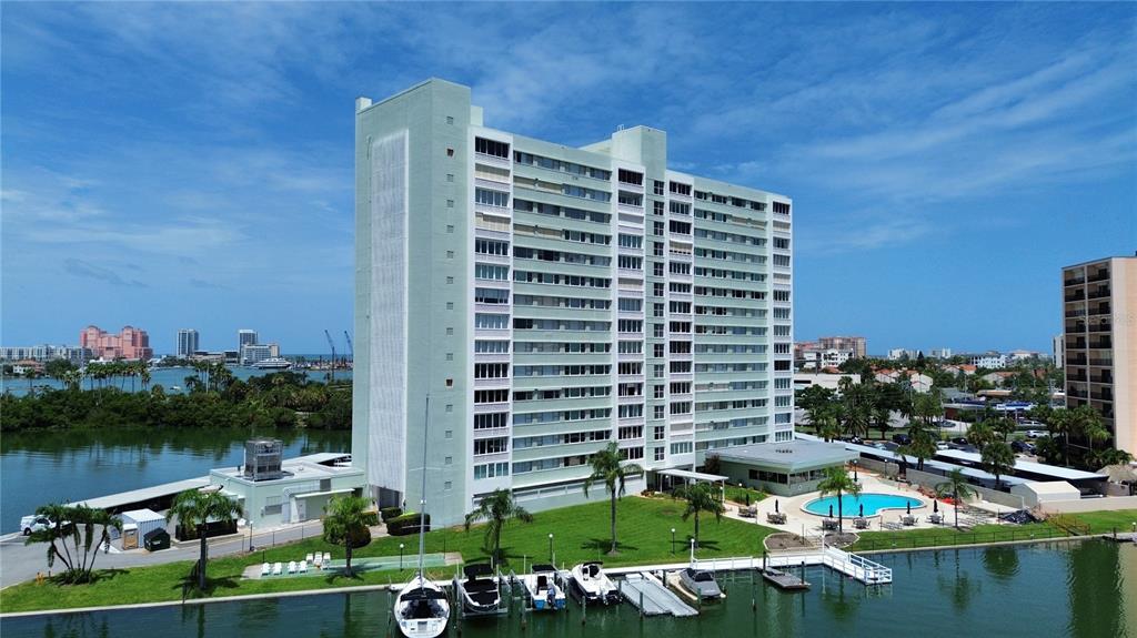 An aerial view of a tall, light green apartment building with a pool and boat slips — 31 ISLAND WAY UNIT 505, CLEARWATER BEACH, FL