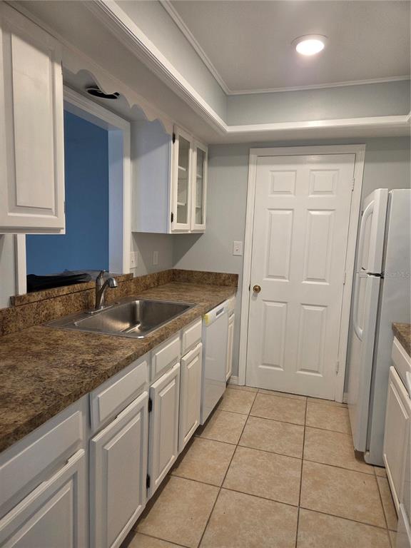 A kitchen features white cabinets, a brown laminate countertop, a stainless sink, and tile flooring — 743 E ALFRED STREET, TAVARES, FL