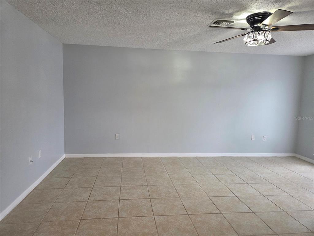 An empty room with light gray walls, beige tile flooring, and a ceiling fan — 743 E ALFRED STREET, TAVARES, FL