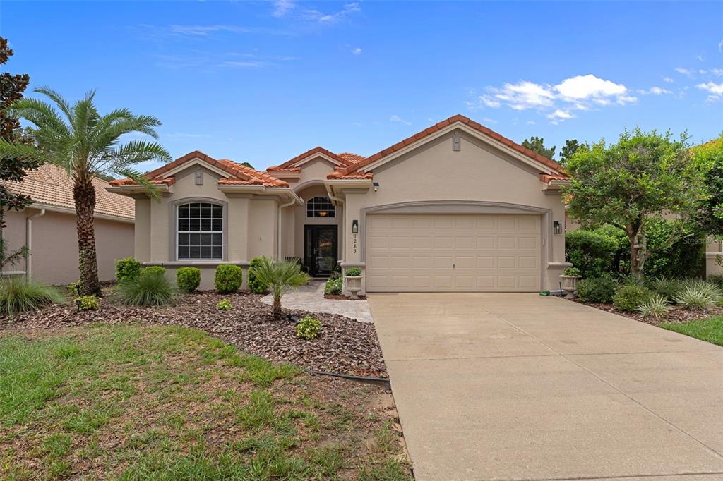 A single-story house with a beige stucco exterior, a tile roof, and a two-car garage — 1283 W DIAMOND SHORE LOOP, HERNANDO, FL