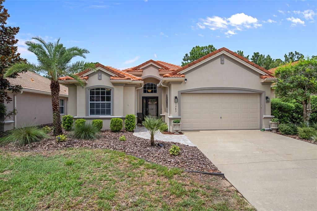 A single-story house with a beige stucco exterior, tile roof, and a two-car garage — 1283 W DIAMOND SHORE LOOP, HERNANDO, FL