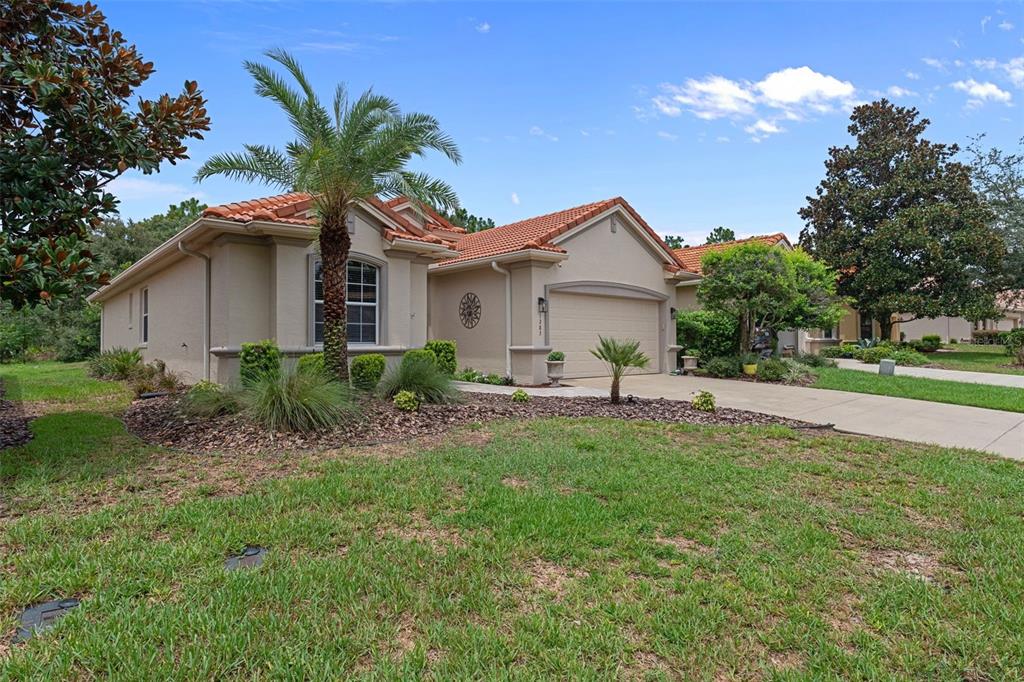 A single-story house with a tile roof, beige stucco exterior, and a two-car garage — 1283 W DIAMOND SHORE LOOP, HERNANDO, FL