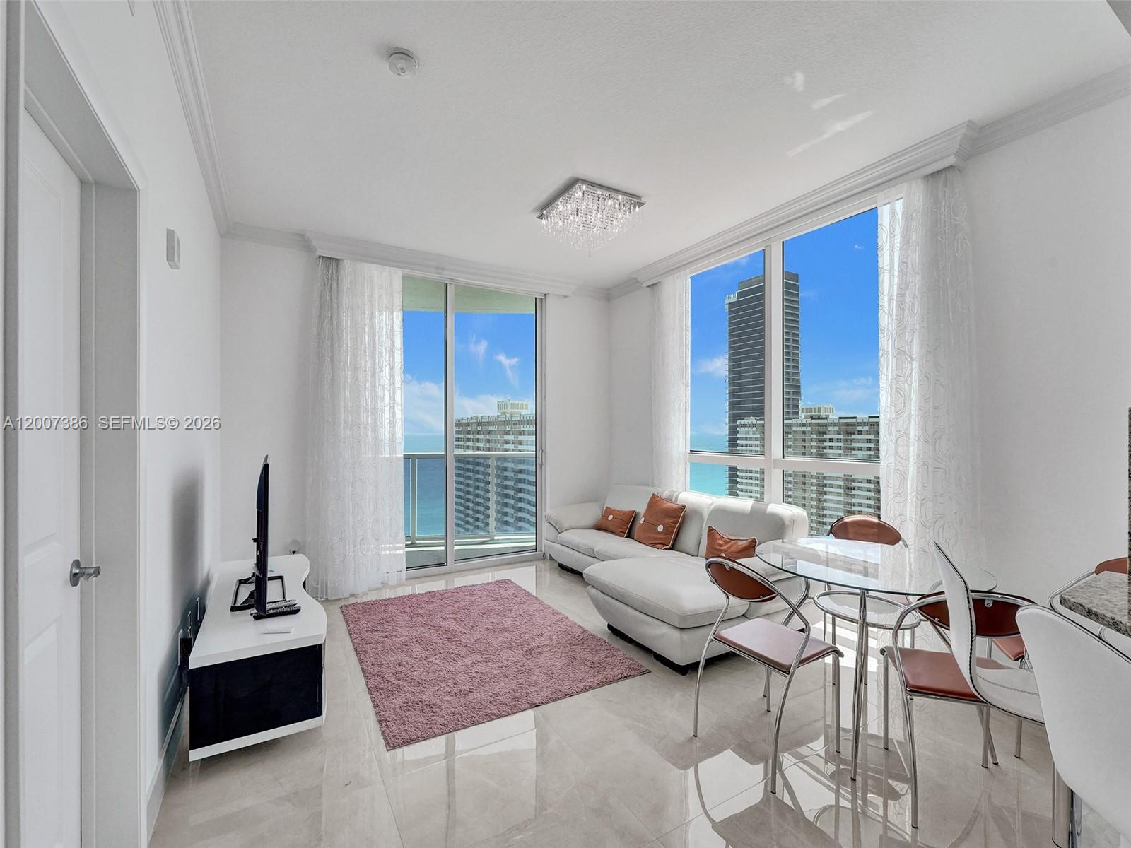A modern living and dining area features white furniture, a pink rug, and ocean views — 1945 S Ocean Dr # 2101, Hallandale Beach FL 33009, HALLANDALE BEACH, FL