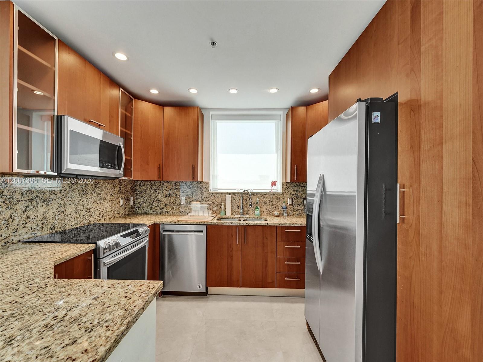 A kitchen features wood cabinets, granite countertops, stainless steel appliances, and a window above the sink — 1945 S Ocean Dr # 2101, Hallandale Beach FL 33009, HALLANDALE BEACH, FL