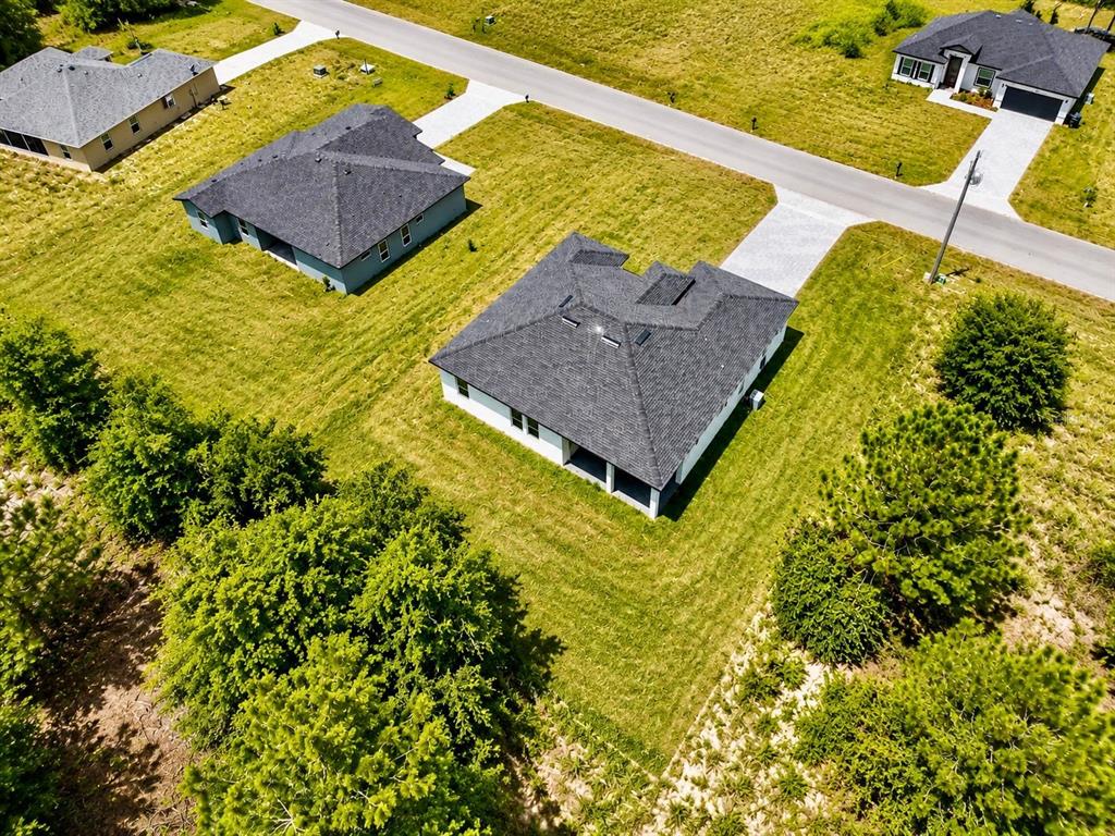 An aerial view shows several suburban houses with dark roofs surrounded by grassy yards — 15775 SW 59TH AVENUE ROAD, OCALA, FL