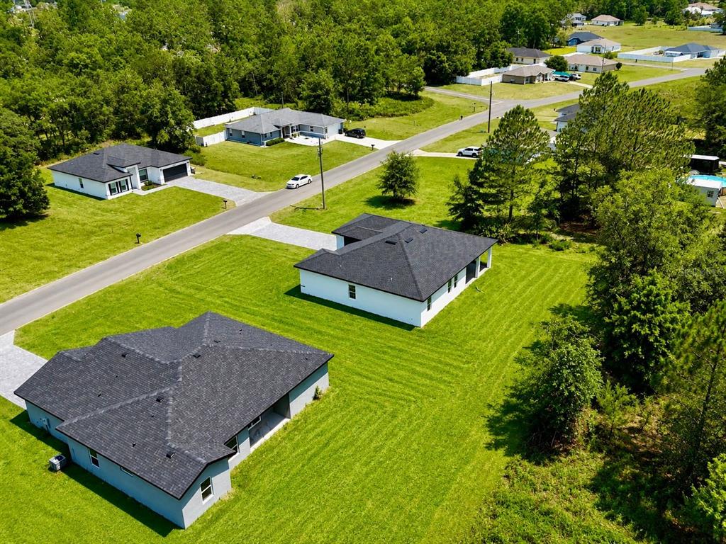 An aerial view shows three modern single-family homes situated on large, grassy lots — 15775 SW 59TH AVENUE ROAD, OCALA, FL
