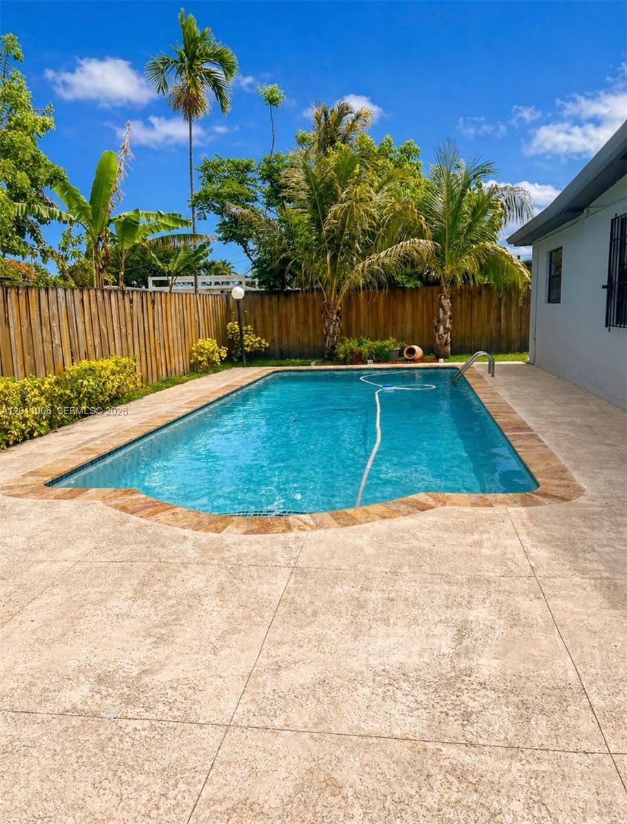 A rectangular swimming pool sits in a backyard with a wooden fence and palm trees — 4825 SW 111th Ave, Miami FL 33165, MIAMI, FL