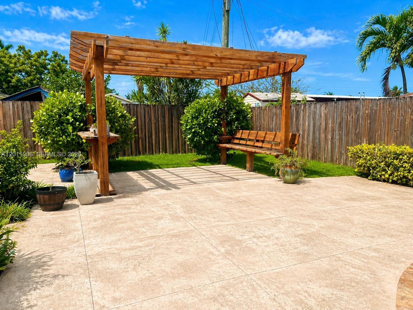 A wooden pergola with a built-in bench sits on a paved patio in a backyard — 4825 SW 111th Ave, Miami FL 33165, MIAMI, FL