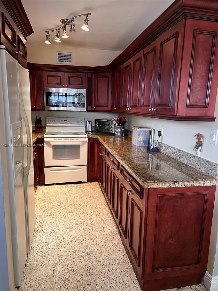 A kitchen features cherry wood cabinets, granite countertops, white appliances, and speckled flooring — 4825 SW 111th Ave, Miami FL 33165, MIAMI, FL