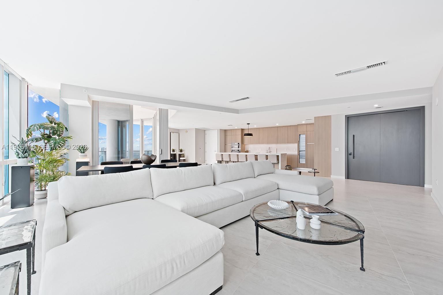A modern, open-concept living room features a white sectional sofa, glass coffee table, and kitchen — 851 NE 1st Ave # 5402, Miami FL 33132, MIAMI, FL