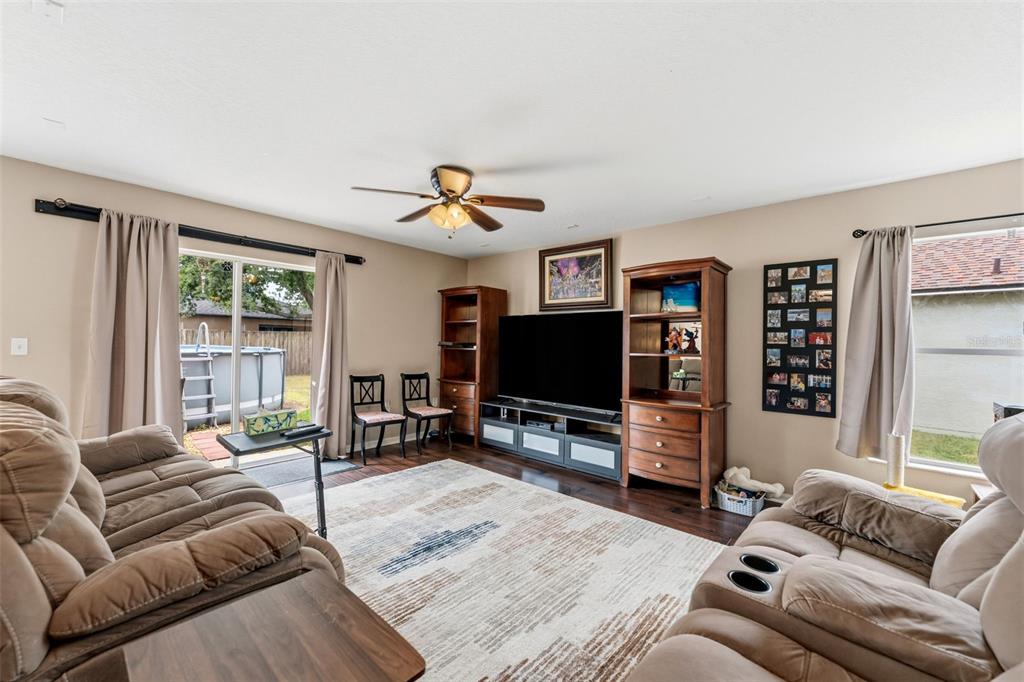 A living room features brown reclining furniture, a large television, and a sliding glass door — 1832 HOLTON ROAD, LAKELAND, FL