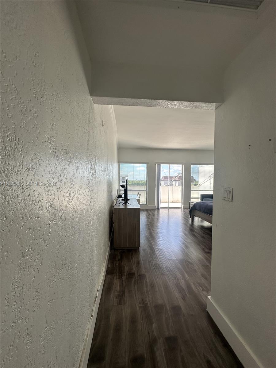 A hallway leads into a living area with wood-look flooring and a glass sliding door — 700 Biltmore Way # 1216, Coral Gables FL 33134, CORAL GABLES, FL