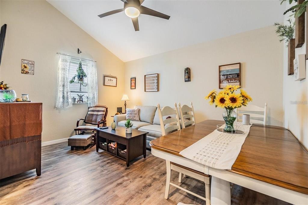 A living and dining area features wood-look flooring, a vaulted ceiling, and a ceiling fan — 1265 JADE PLACE, CLEARWATER, FL