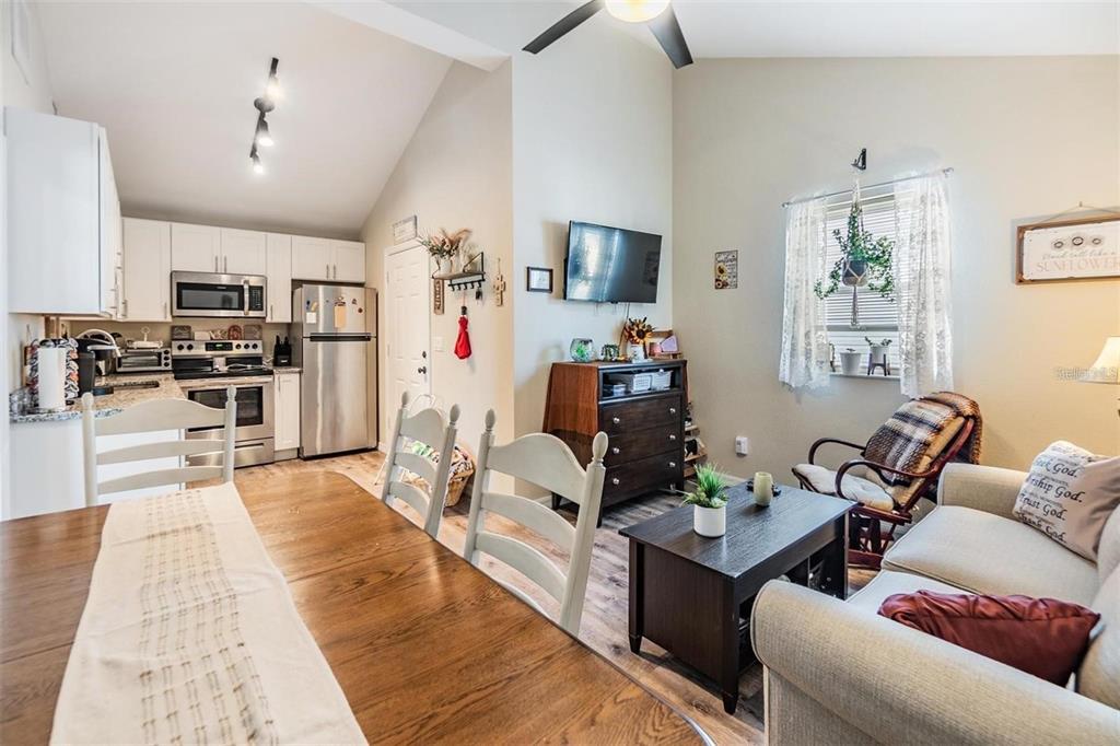 An open-concept kitchen, dining area, and living room with white cabinets and wood-look flooring — 1265 JADE PLACE, CLEARWATER, FL