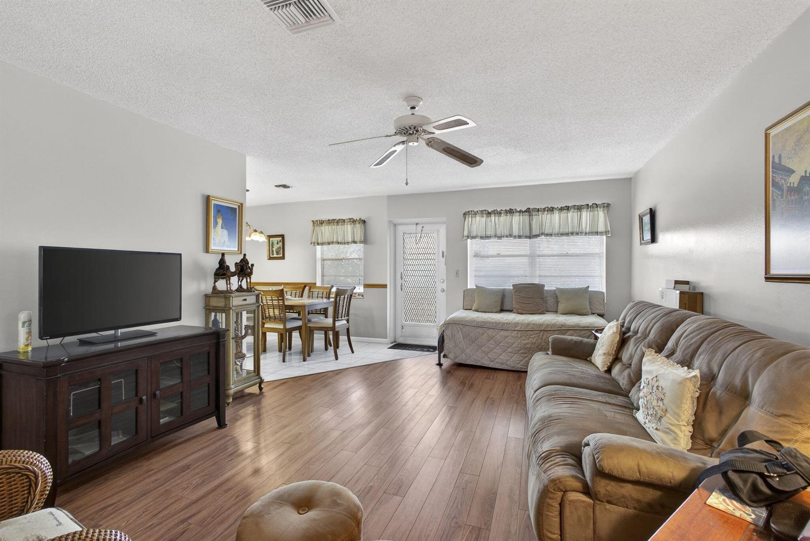 A living room with wood-look flooring, a ceiling fan, and an adjacent dining area — 272 Bedford K, West Palm Beach FL 33417, WEST PALM BEACH, FL