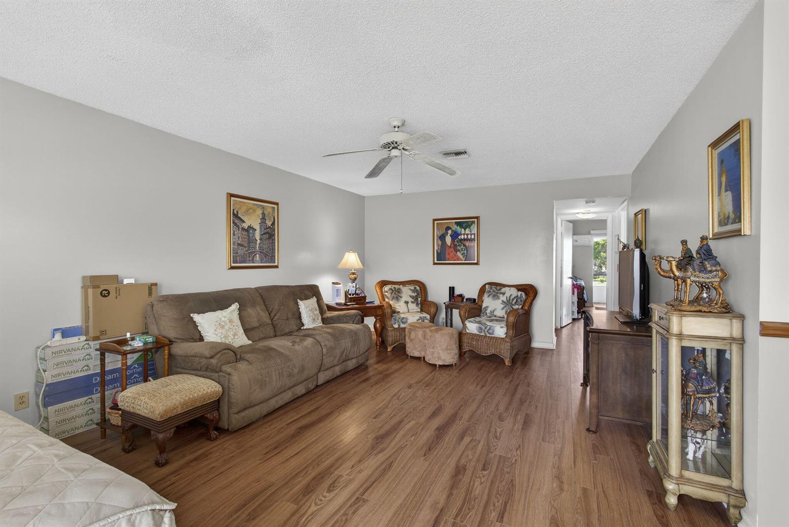 A living room features wood-look flooring, a brown sofa, two wicker chairs, and a ceiling fan — 272 Bedford K, West Palm Beach FL 33417, WEST PALM BEACH, FL