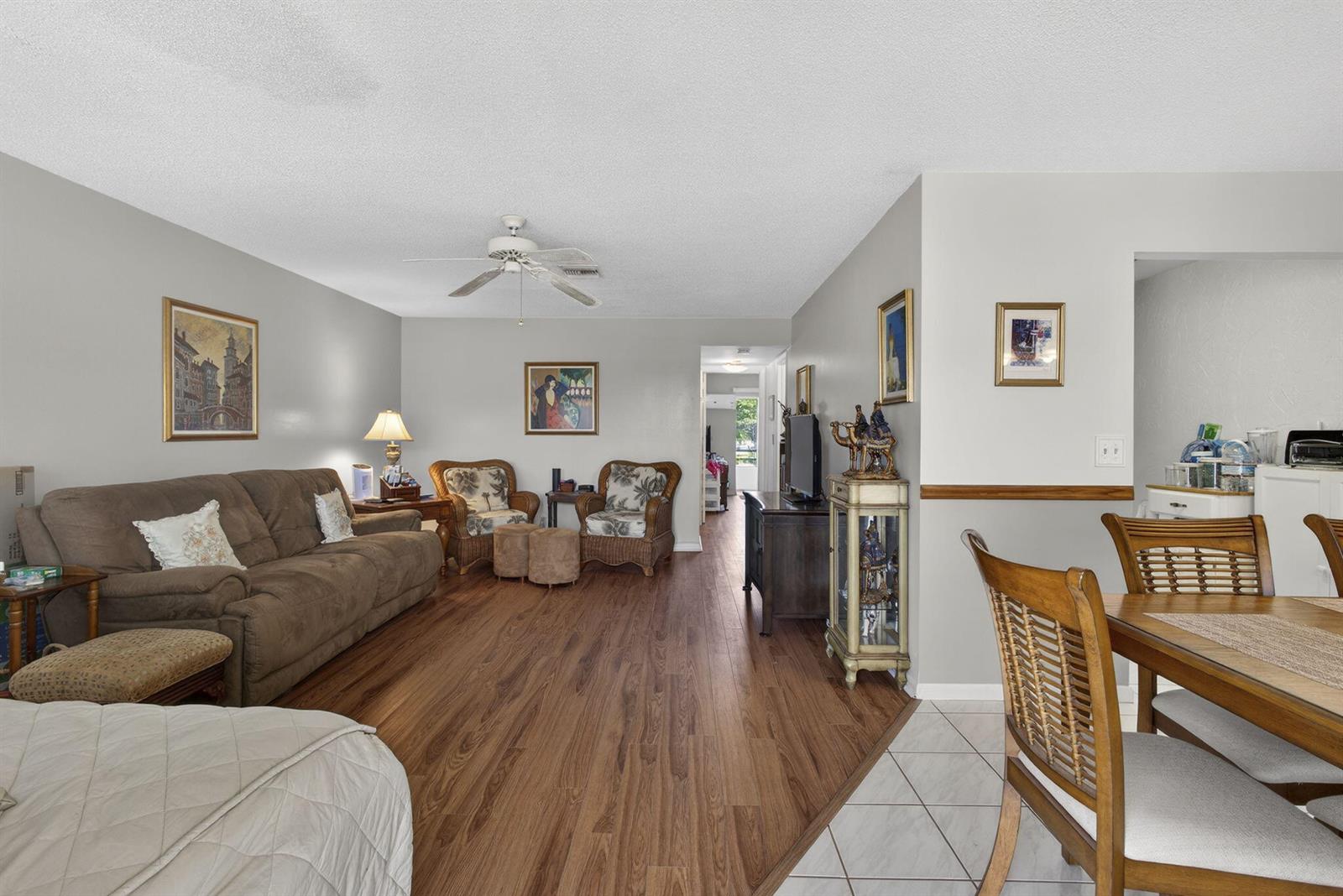 A living room with wood-look flooring flows into a dining area with tiled floors — 272 Bedford K, West Palm Beach FL 33417, WEST PALM BEACH, FL