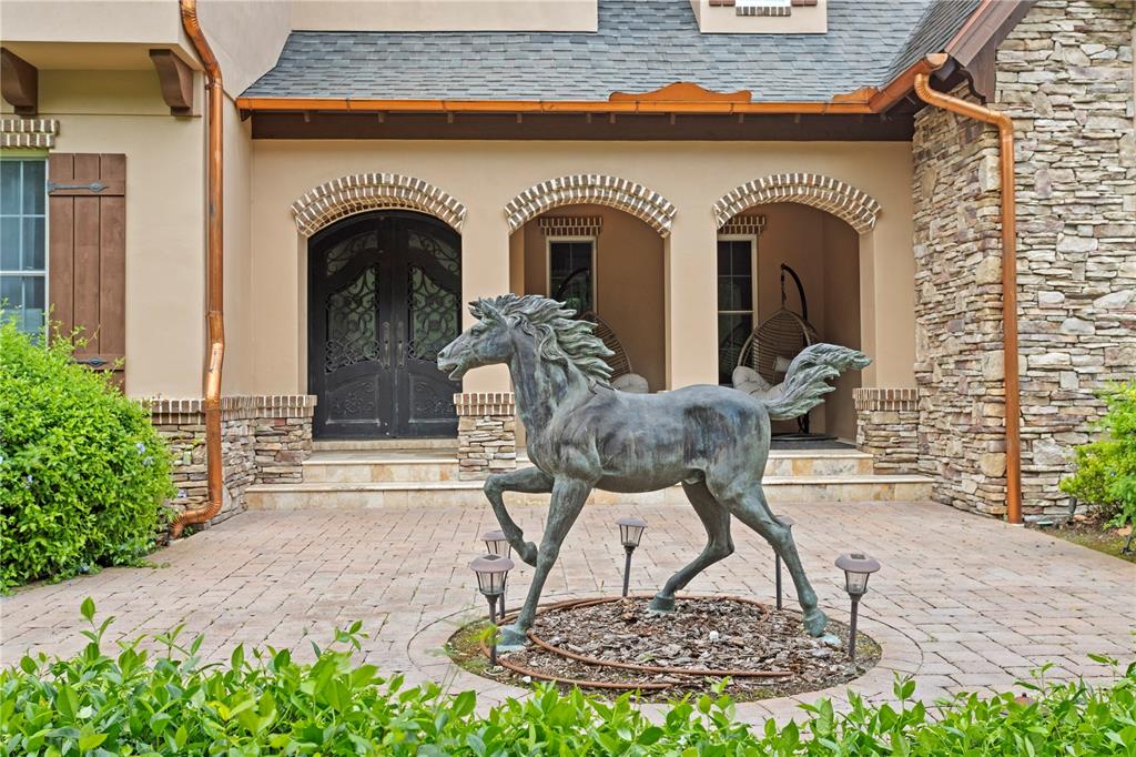 A bronze horse statue stands on a paved patio in front of a house entrance — 11410 TROTTING DOWN DRIVE, ODESSA, FL
