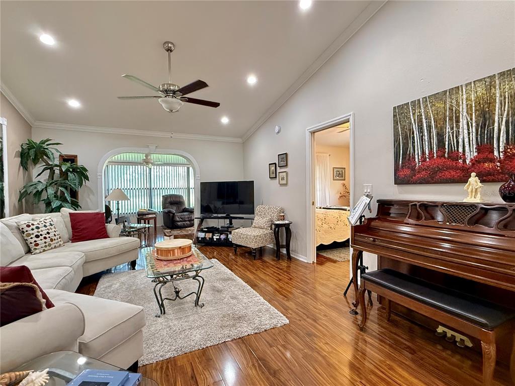 A living room features hardwood floors, a sectional sofa, a piano, and a television — 1742 W ORANGEWOOD PLACE, AVON PARK, FL