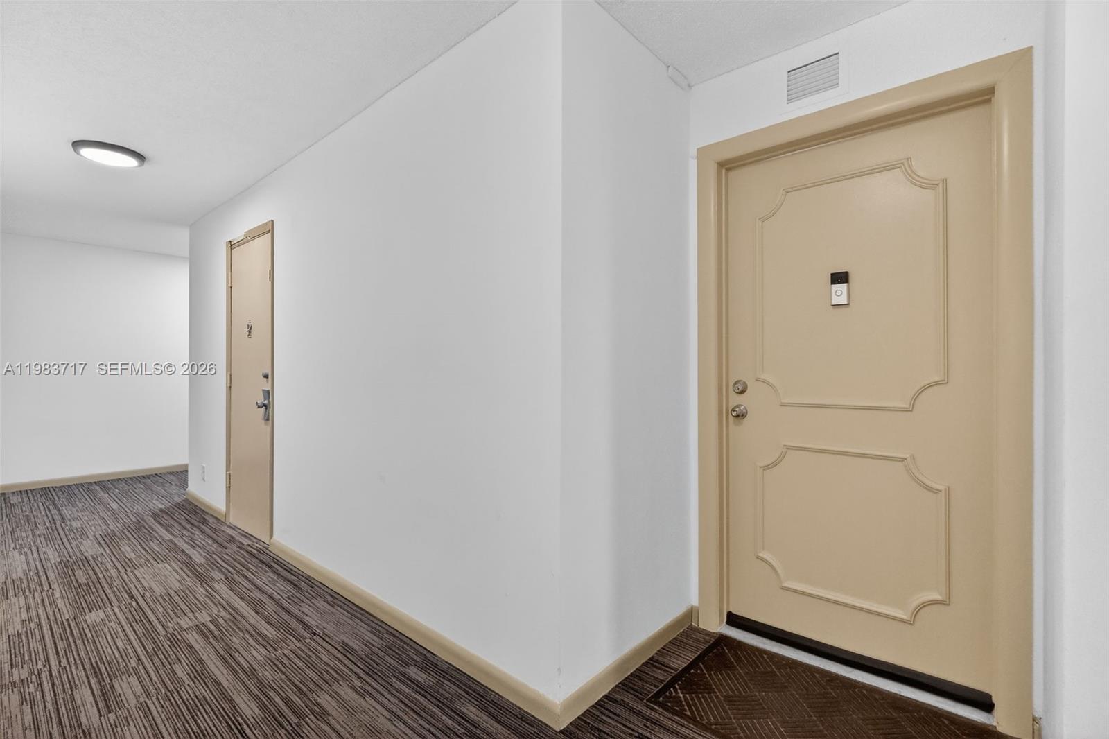 A hallway features white walls, patterned carpet, and two beige doors with decorative panels — 1410 S Ocean Dr # 601, Hollywood FL 33019, HOLLYWOOD, FL