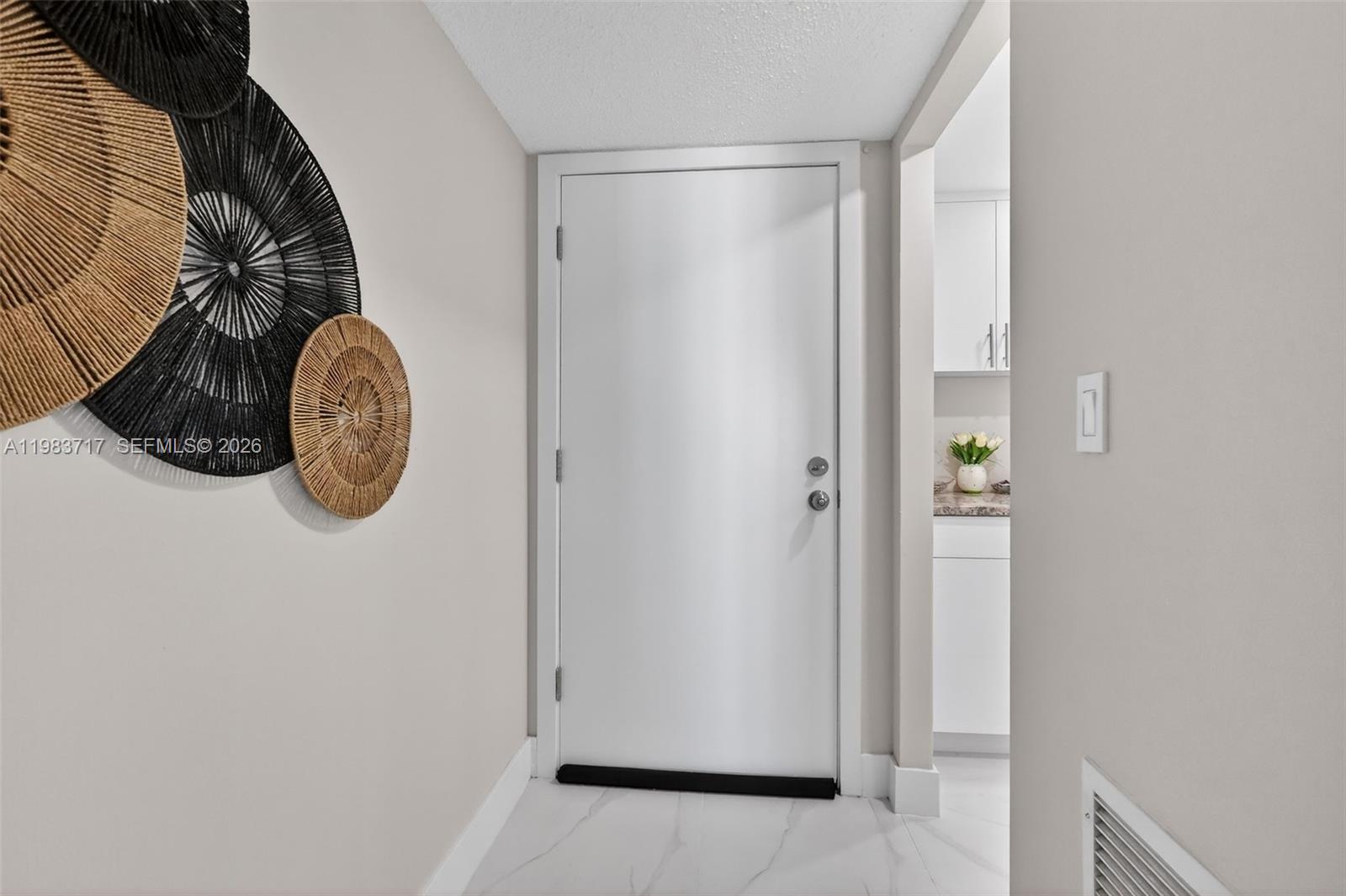 A white door with a black draft stopper stands in a hallway with wall decor — 1410 S Ocean Dr # 601, Hollywood FL 33019, HOLLYWOOD, FL