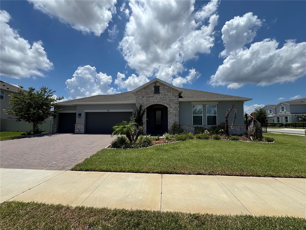A single-story house with a stone facade, a paved driveway, and a green lawn — 715 BLUE CITRUS LANE, MINNEOLA, FL